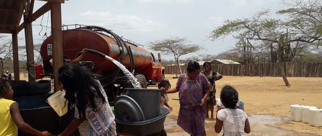 Carrotanque descargando agua dulce mientras las familias llenan sus recipientes