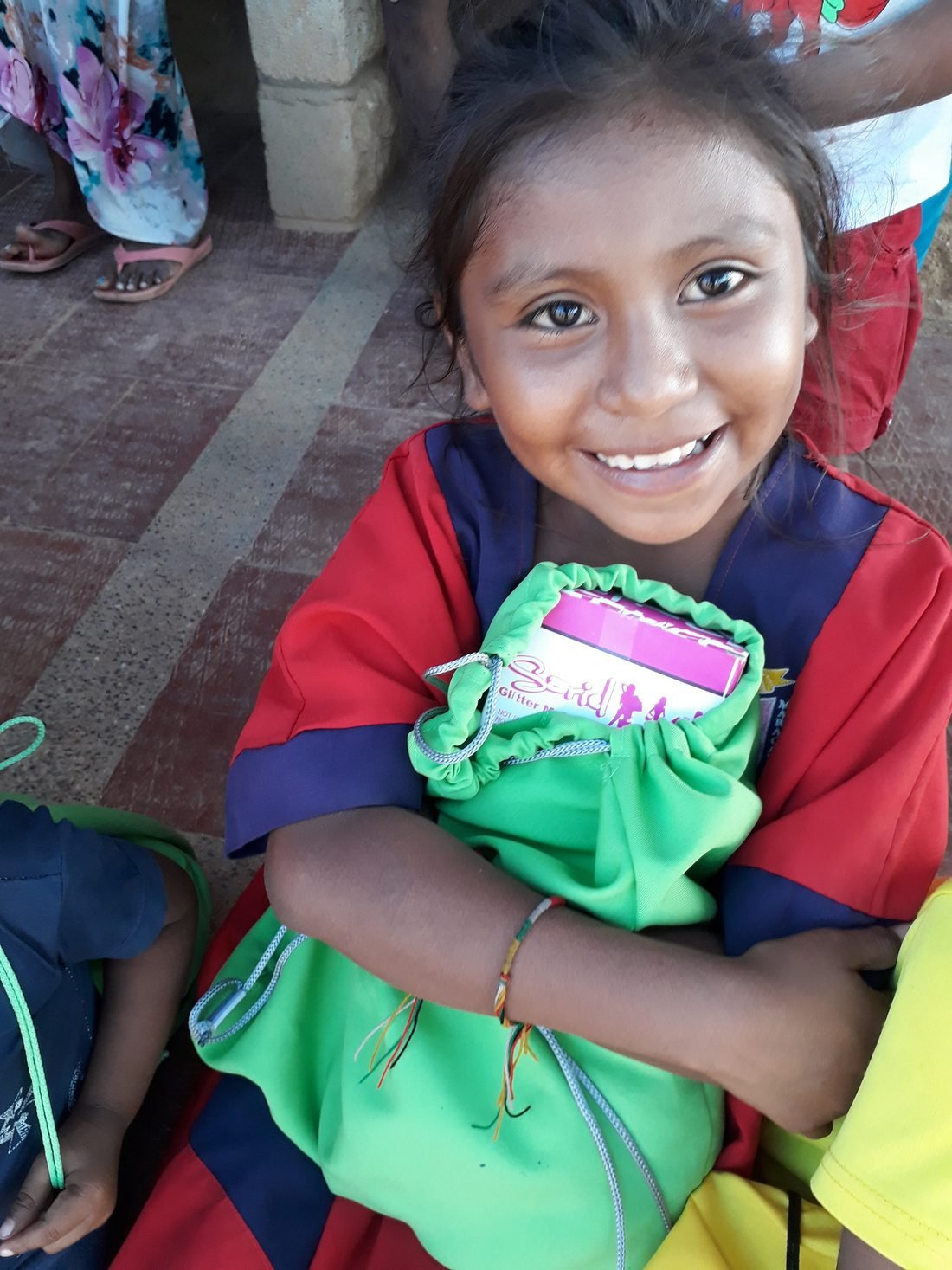 Niña wayúu sonriendo mientras muestra el regalo que acaba de recibir